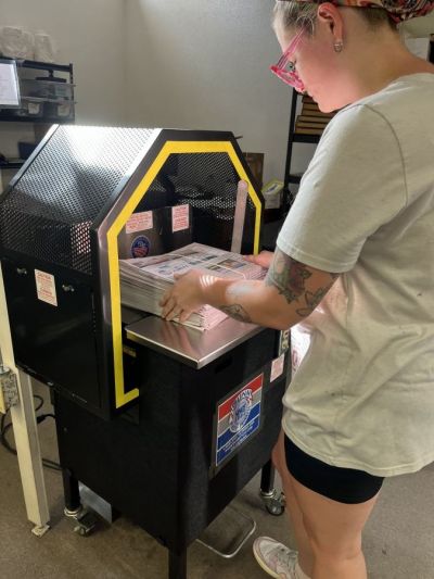 Emily Whittington bundles copies of the newspaper for mailing, as per instructions from the U.S. Postal Service. The bundling machine was purchased from the B.H. Bunn Co. in nearby Lakeland, where it was made, and it has been the key to The Beacon saving money by processing its own mailing. Beacon staffers were especially glad that the machine uses string, rather than plastic strapping.
