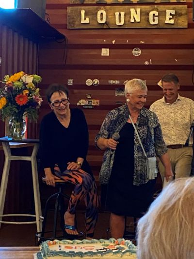 Sue Orsen is pictured on stage at The Victoria Burrow being toasted and roasted (with friends Nan Emmer and John Mugford, former editor of the Chanhassen Villager).